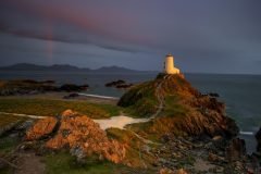 Twr Mawr Lighthouse Llanddwyn Island with spectacular rainbow over the mountains of Snowdonia Eryri