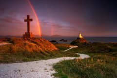 Twr Mawr Lighthouse Llanddwyn Island with spectacular rainbow over the mountains of Snowdonia Eryri