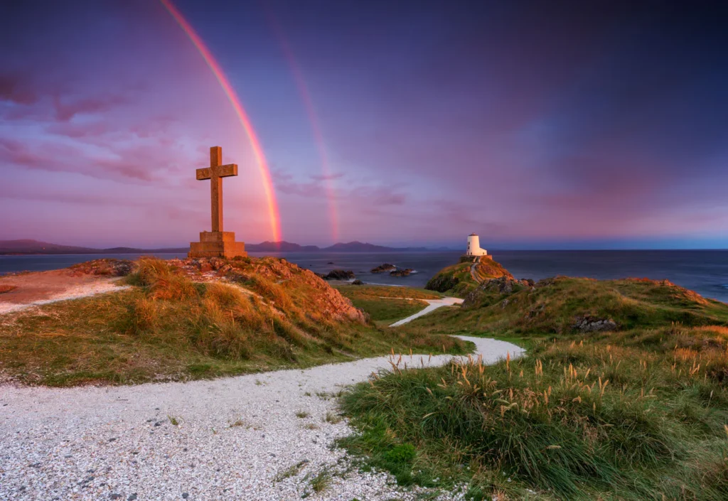 Twr Mawr Lighthouse Llanddwyn Island with spectacular rainbow over the mountains of Snowdonia Eryri